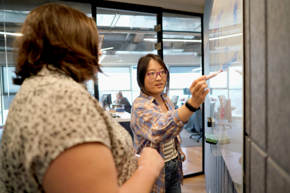 Two people standing at a whiteboard