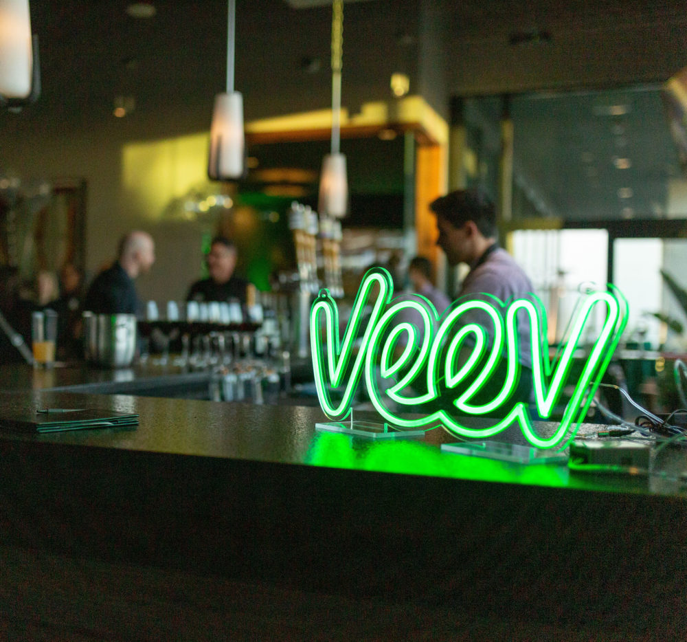 The Veev logo illuminated in a neon sign